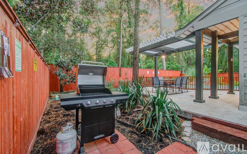 A BBQ grill is on a patio with a table and chairs.