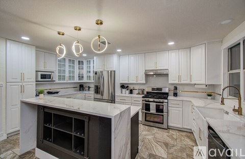 A modern kitchen with white cabinets and marble countertops.