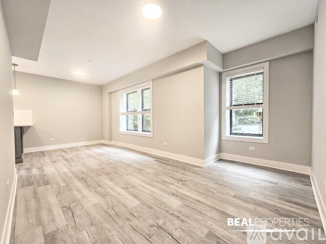 A spacious room with light grey walls and a wooden floor.
