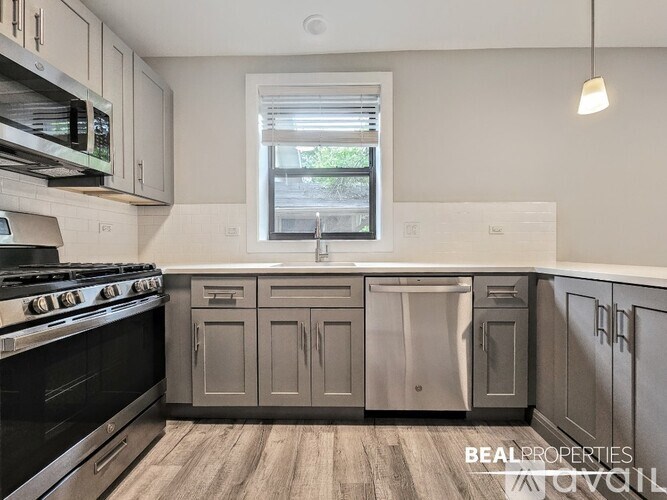A kitchen with a black stove top oven and grey cabinets.