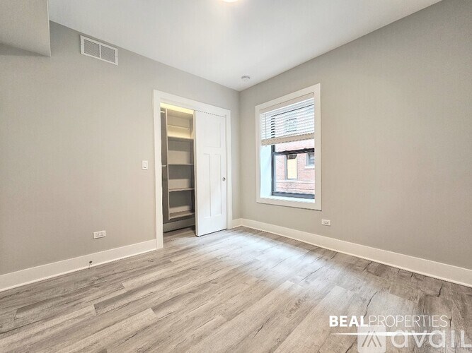 A spacious room with a doorway leading to another room and a window with blinds.