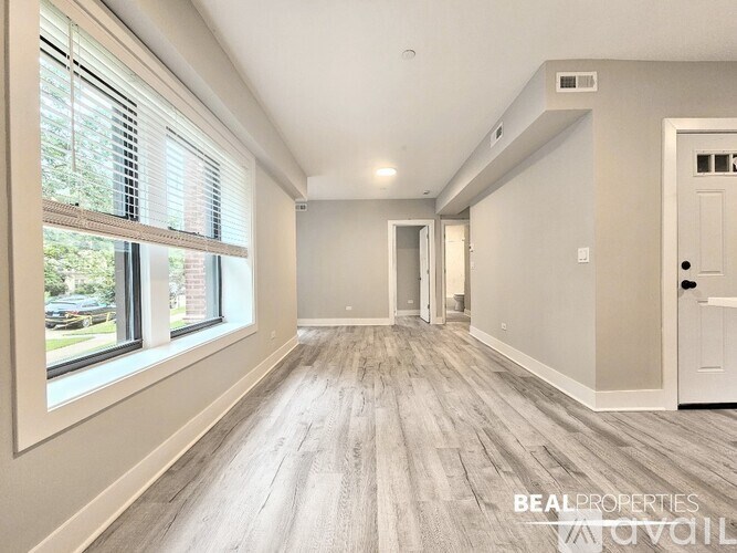 A spacious room with wooden flooring and a white door.