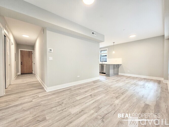 A spacious room with wooden flooring and a door on the left.