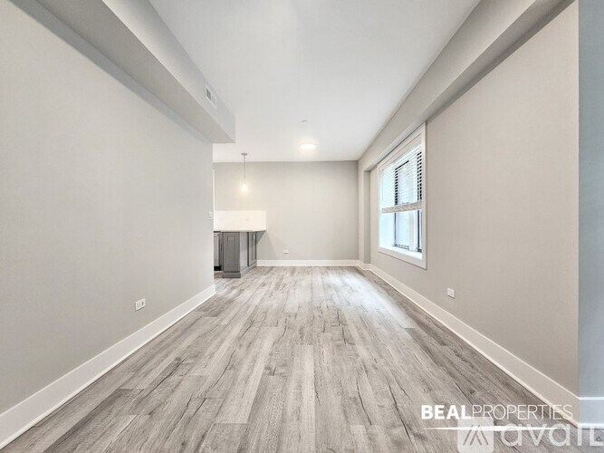 A spacious room with wooden flooring and a window on the right side.