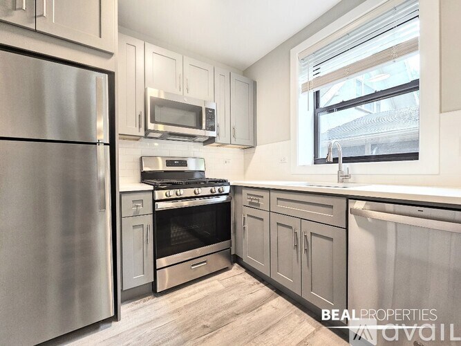 A kitchen with a refrigerator, oven, microwave, and sink.