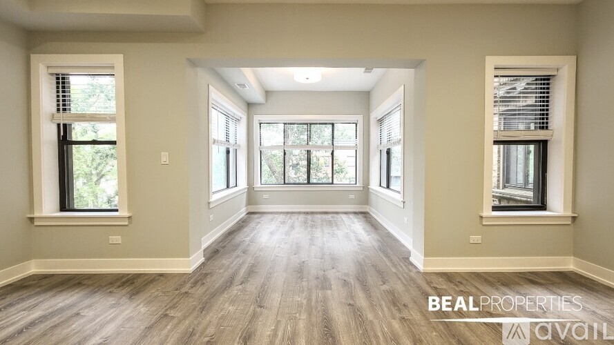 A spacious room with wooden flooring and large windows on both sides.