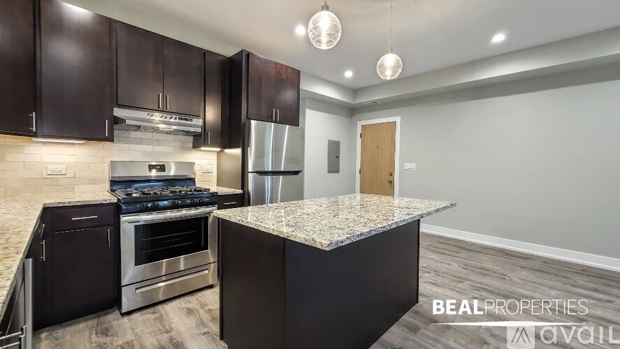 A modern kitchen with dark brown cabinets and a granite countertop.