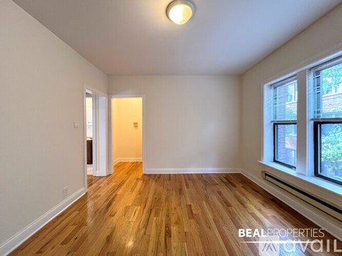 A room with wooden floors and a window on the right side.