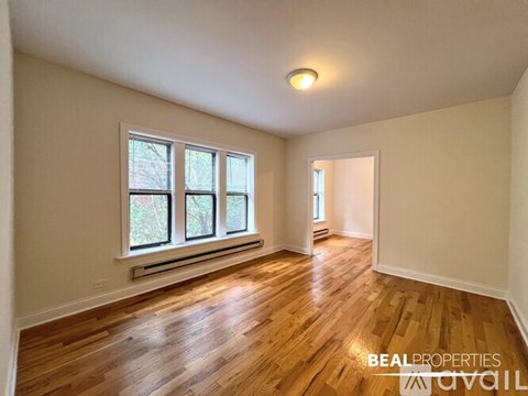 A room with wooden floors and a window with a view of trees.