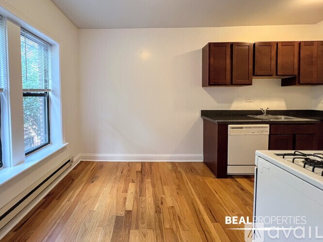A kitchen with a white stove and wooden floors.