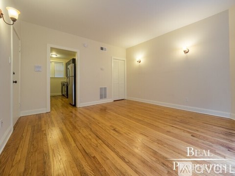 A spacious room with wooden flooring and white walls.