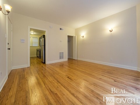 A spacious room with wooden flooring and white walls.