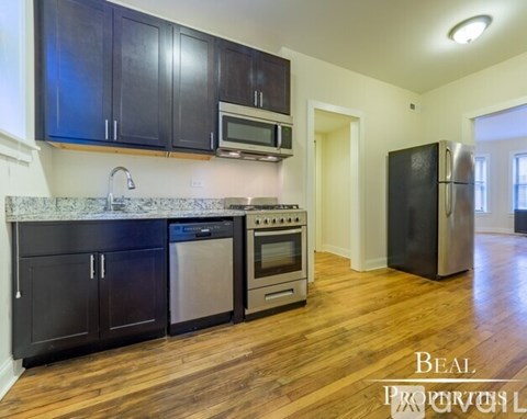 A kitchen with black cabinets and a wooden floor.