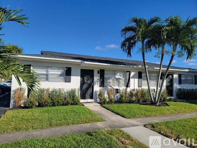 A white house with a black roof and a palm tree in front.