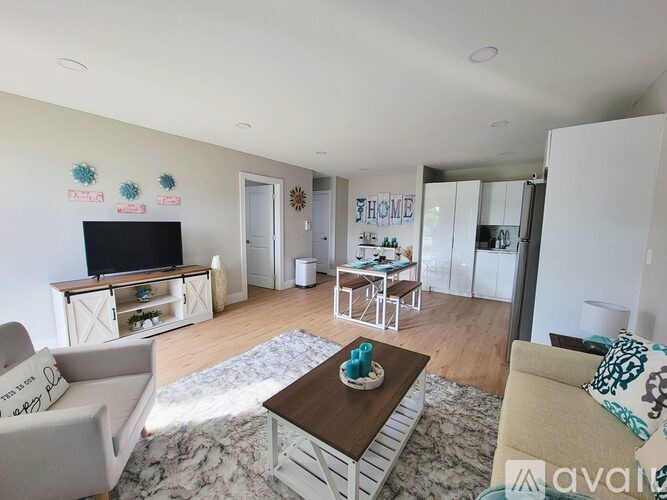 A living room with a white sofa, a wooden coffee table, and a TV on a cabinet.