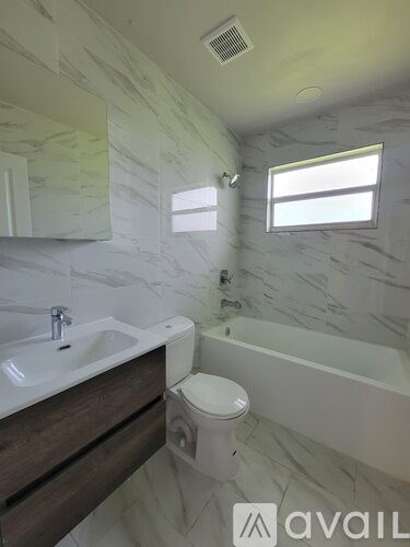 A bathroom with a marble wall and a white toilet.