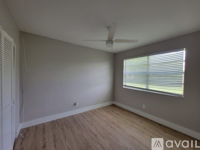 A room with a ceiling fan and a window with blinds.