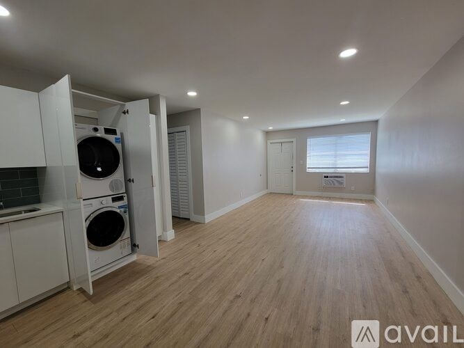 A room with wooden flooring and a washing machine in the corner.