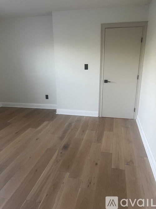 A room with a white door and wooden flooring.