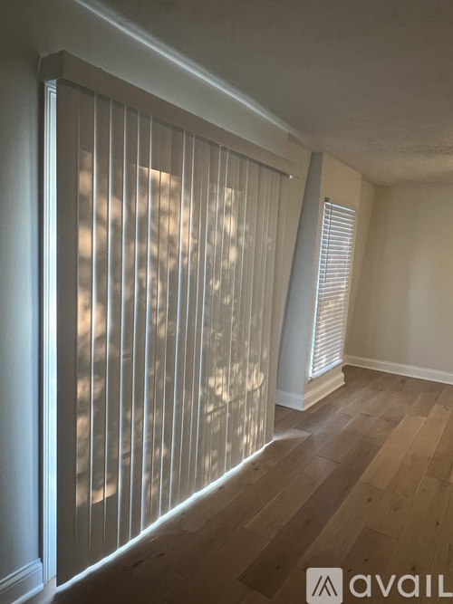 A room with a window covered by vertical blinds.