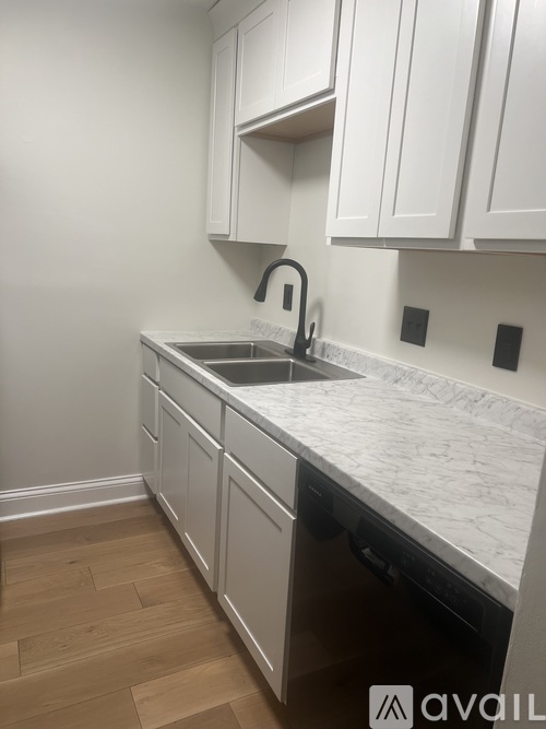 A kitchen with white cabinets and a marble countertop.