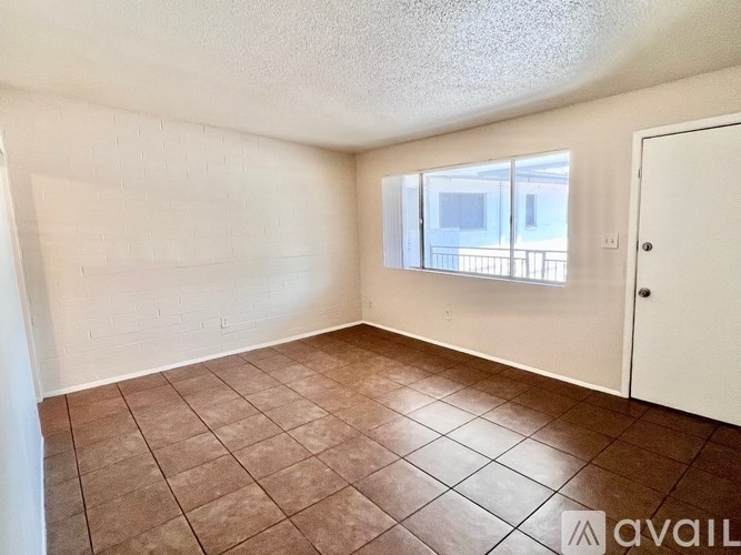 A room with brown tiles on the floor and a window with a view of a balcony.