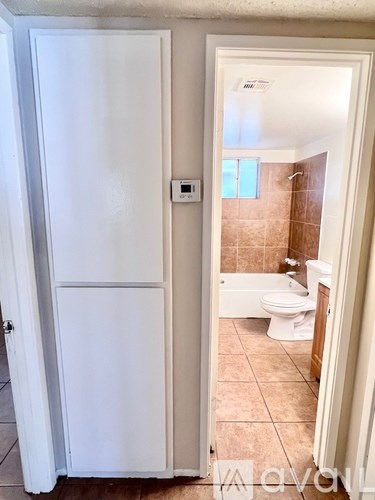 A white door is open to a bathroom with a toilet and tub.