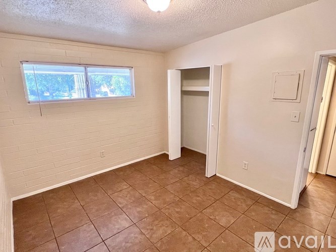 A room with a tiled floor and a window with blinds.
