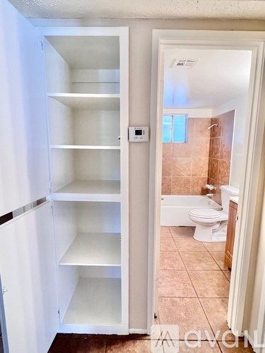 A white pantry door is open to a bathroom.