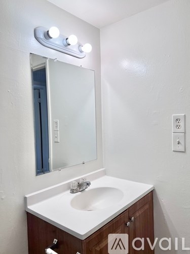 A bathroom with a sink, mirror and lights.