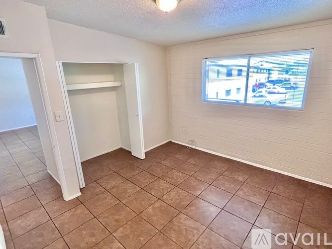 A room with a tiled floor and a window showing a parking lot outside.