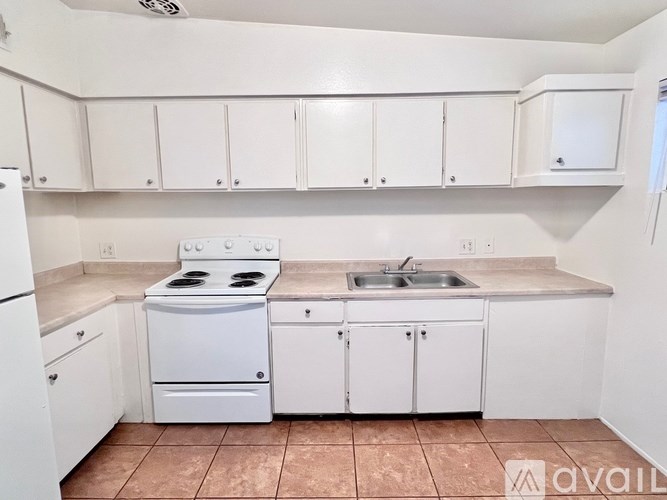 A kitchen with white cabinets and a white stove top oven.