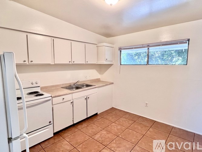 A kitchen with white appliances and cabinets is available for rent.