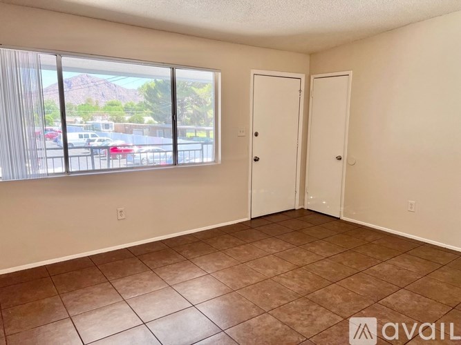 A room with two doors and a window overlooking a parking lot.