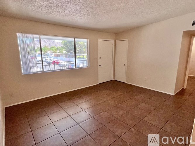 A room with brown tiles and a window showing a parking lot outside.