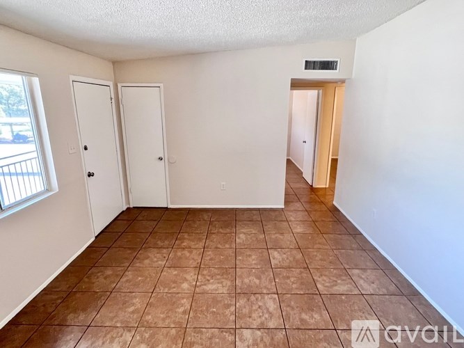 A room with tile flooring and two doors.