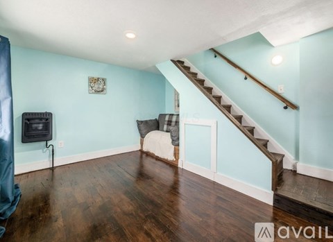 A living room with a blue wall and a wood floor.