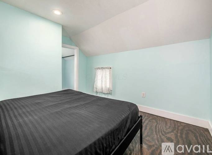 A bedroom with a bed and a window with curtains.