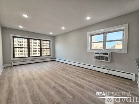 A spacious room with a large window and a wall-mounted air conditioning unit.