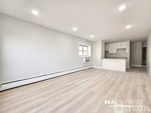 A spacious room with wooden flooring and white walls.
