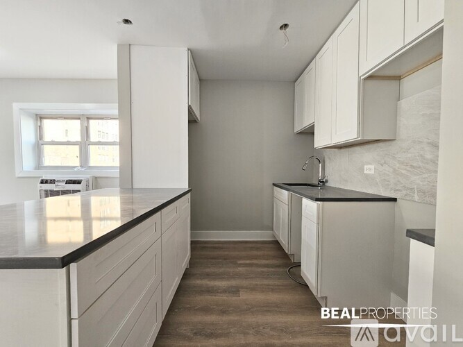 A kitchen with white cabinets and a black countertop.