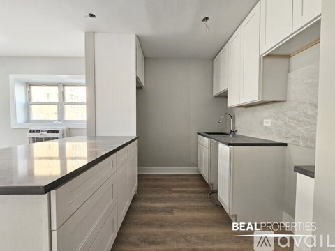 A kitchen with white cabinets and a black countertop.