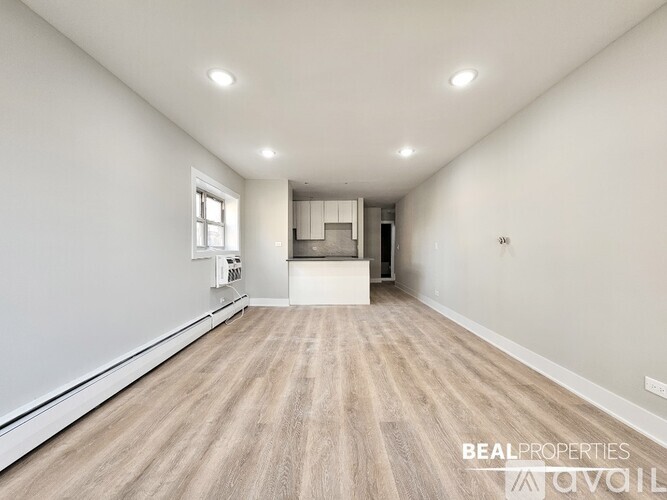 A spacious room with wooden flooring and white walls.