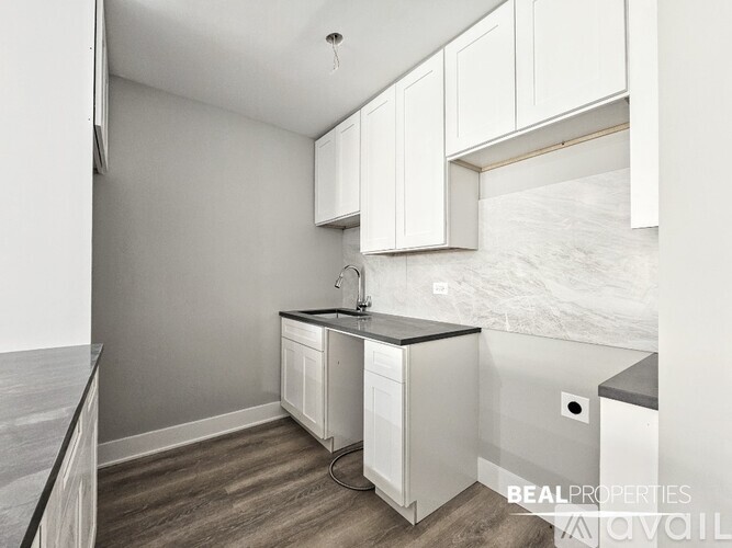 A kitchen with white cabinets and a black countertop.