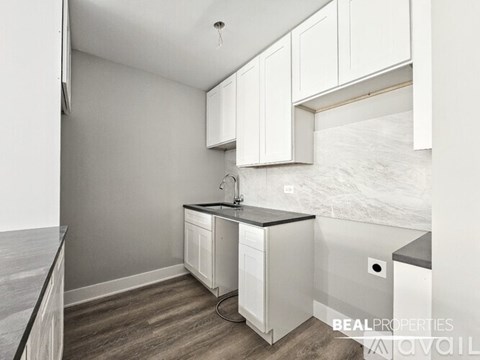 A kitchen with white cabinets and a black countertop.