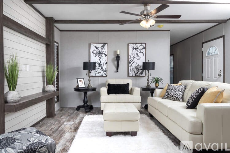 A living room with a white couch, a black and white rug, and a wooden floor.