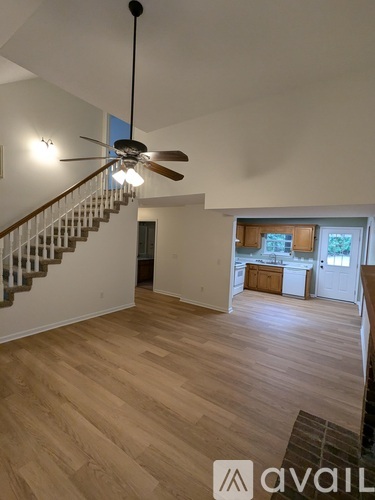 A living room with a staircase and a ceiling fan.
