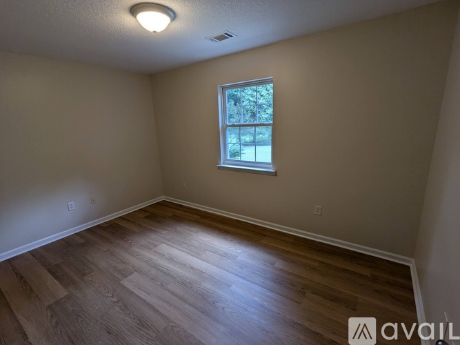 A room with wooden flooring and a window.