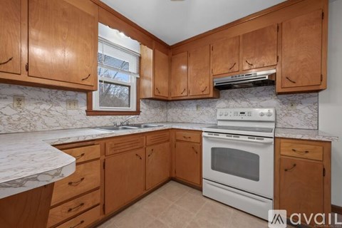 A kitchen with wooden cabinets and a white stove top oven.