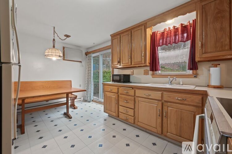 A room with a carpeted floor, a ceiling fan, and a window with curtains.